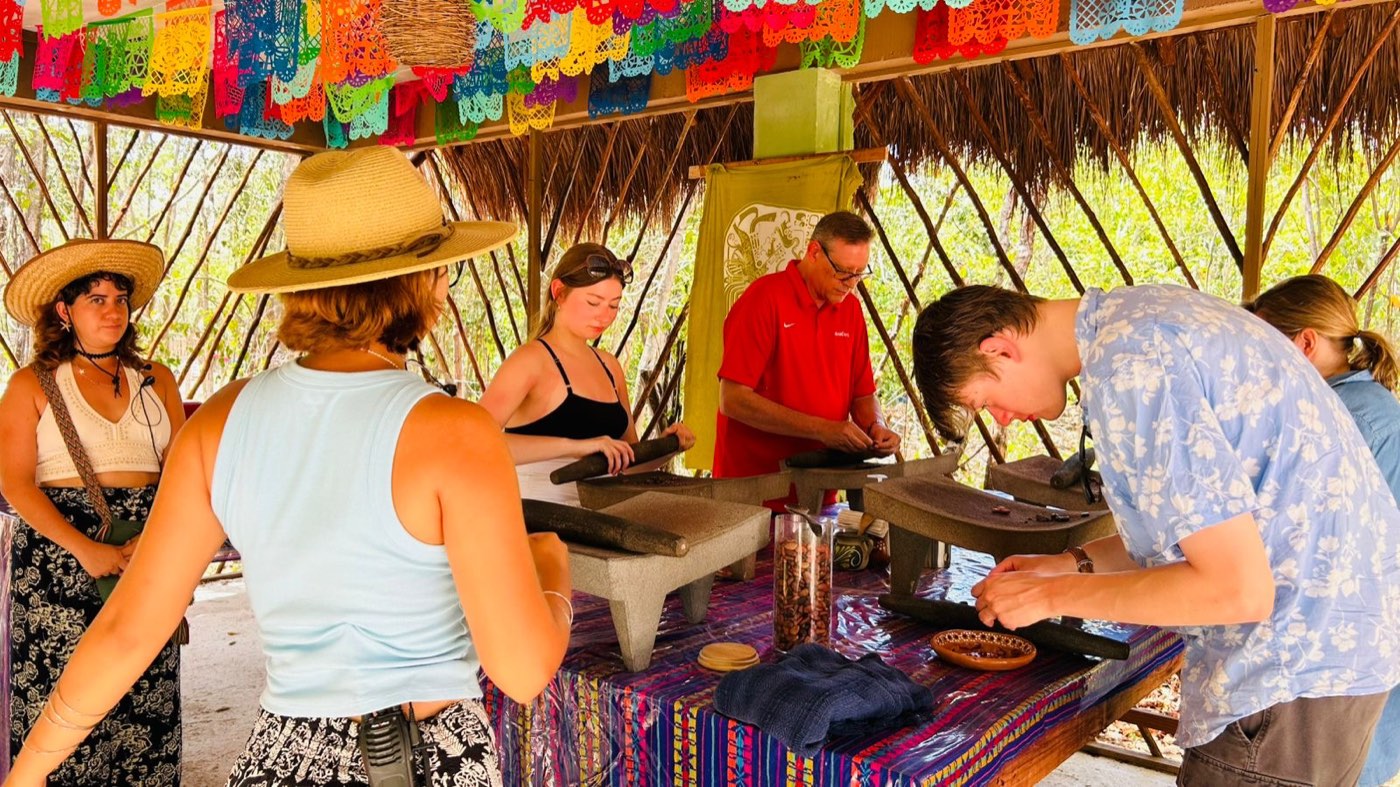 Guests grinding cacao under the papel picado
